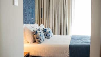 Una habitación de hotel con cama, almohadas, cortinas y una pared con textura.