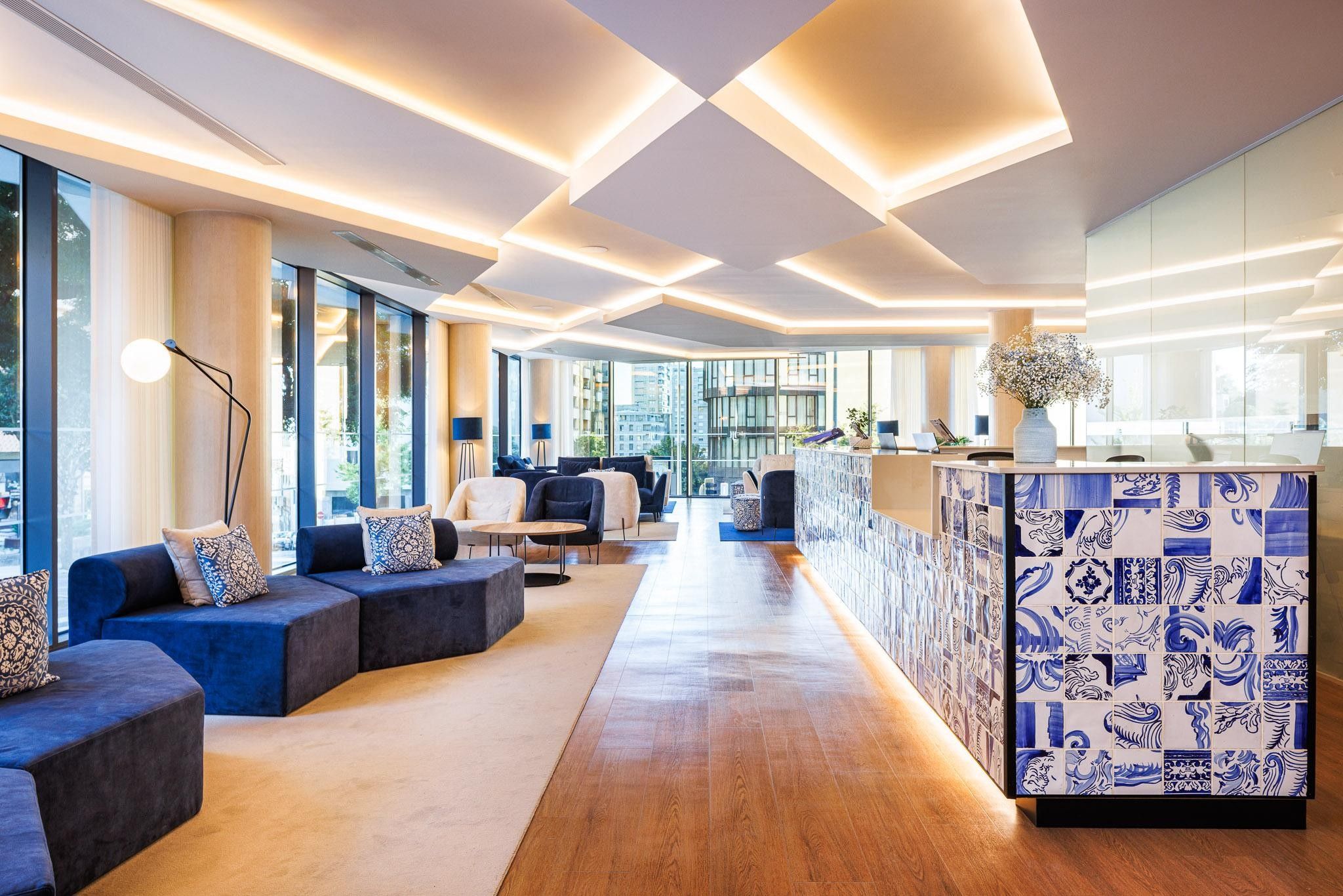 A modern hotel lobby with seating areas, a reception desk, and large windows offering views.