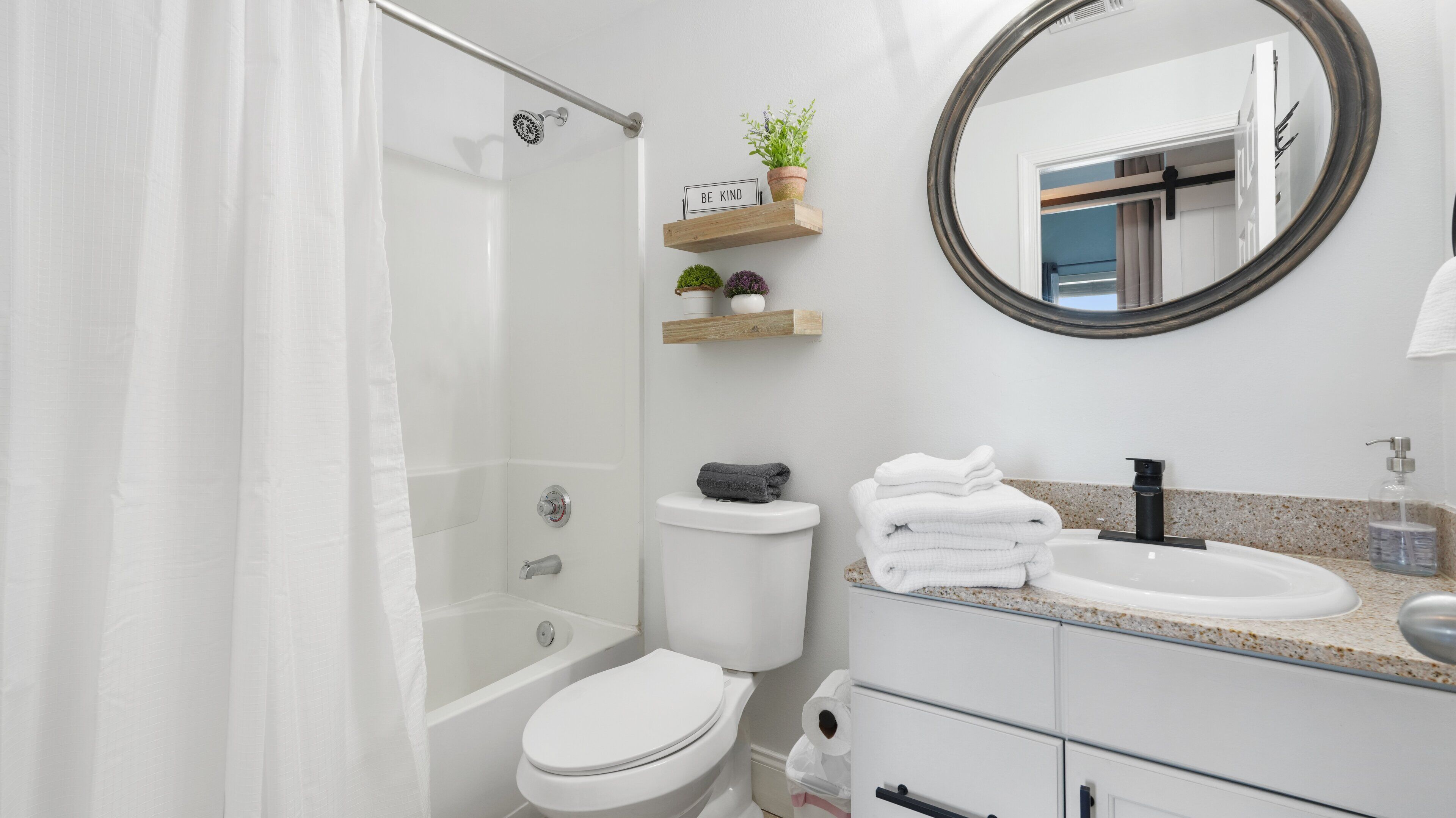 A modern bathroom with a shower, toilet, sink, and mirror.