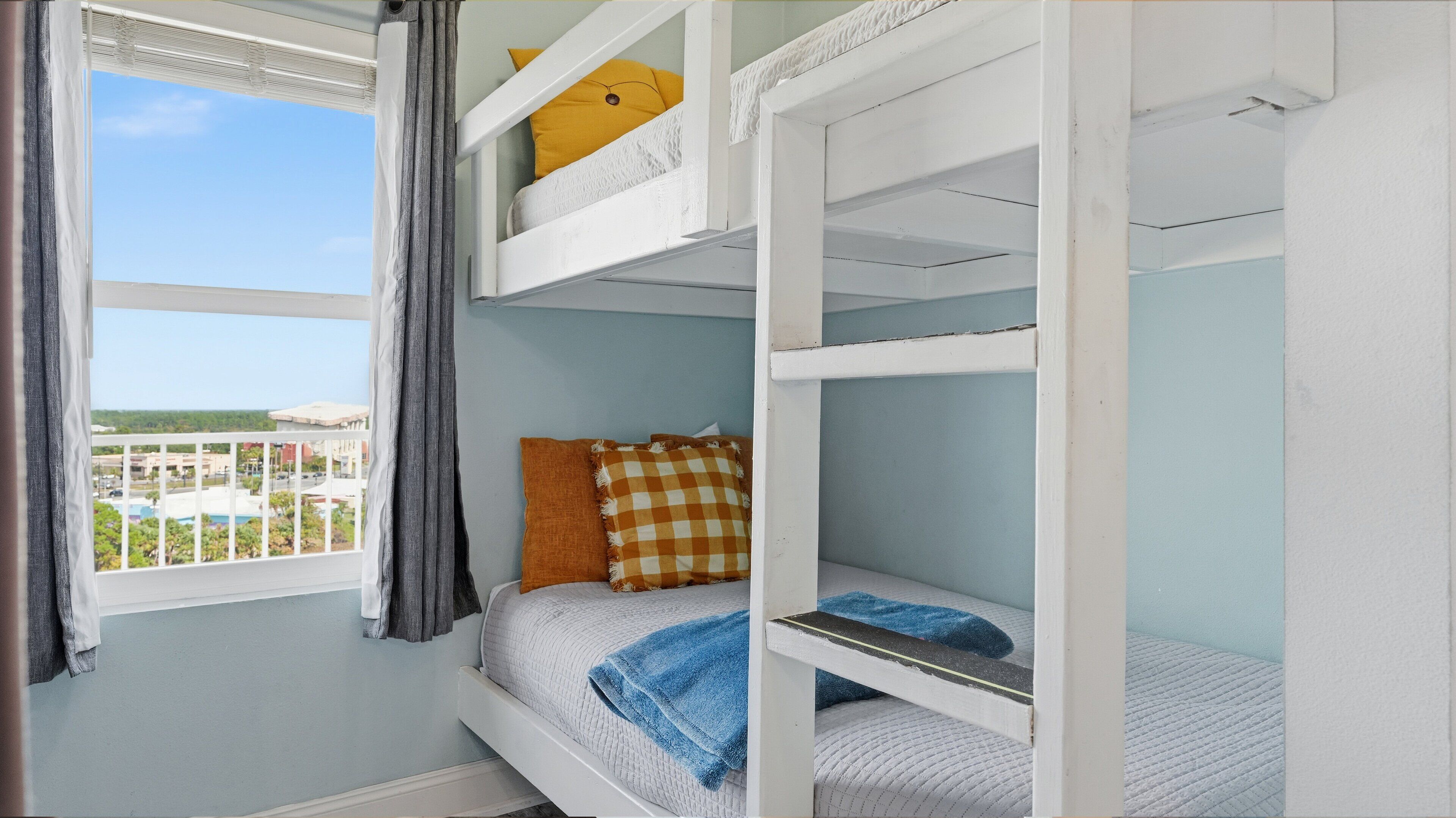 A bunk bed room with a window view of a pool and buildings.