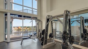 Un gimnasio con equipo de levantamiento de pesas y amplias ventanas con vistas a un paisaje pintoresco.