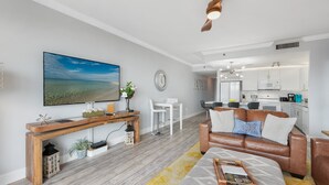 Una sala de estar moderna con un mueble consola de madera, un sofá blanco y un televisor de pantalla plana grande.