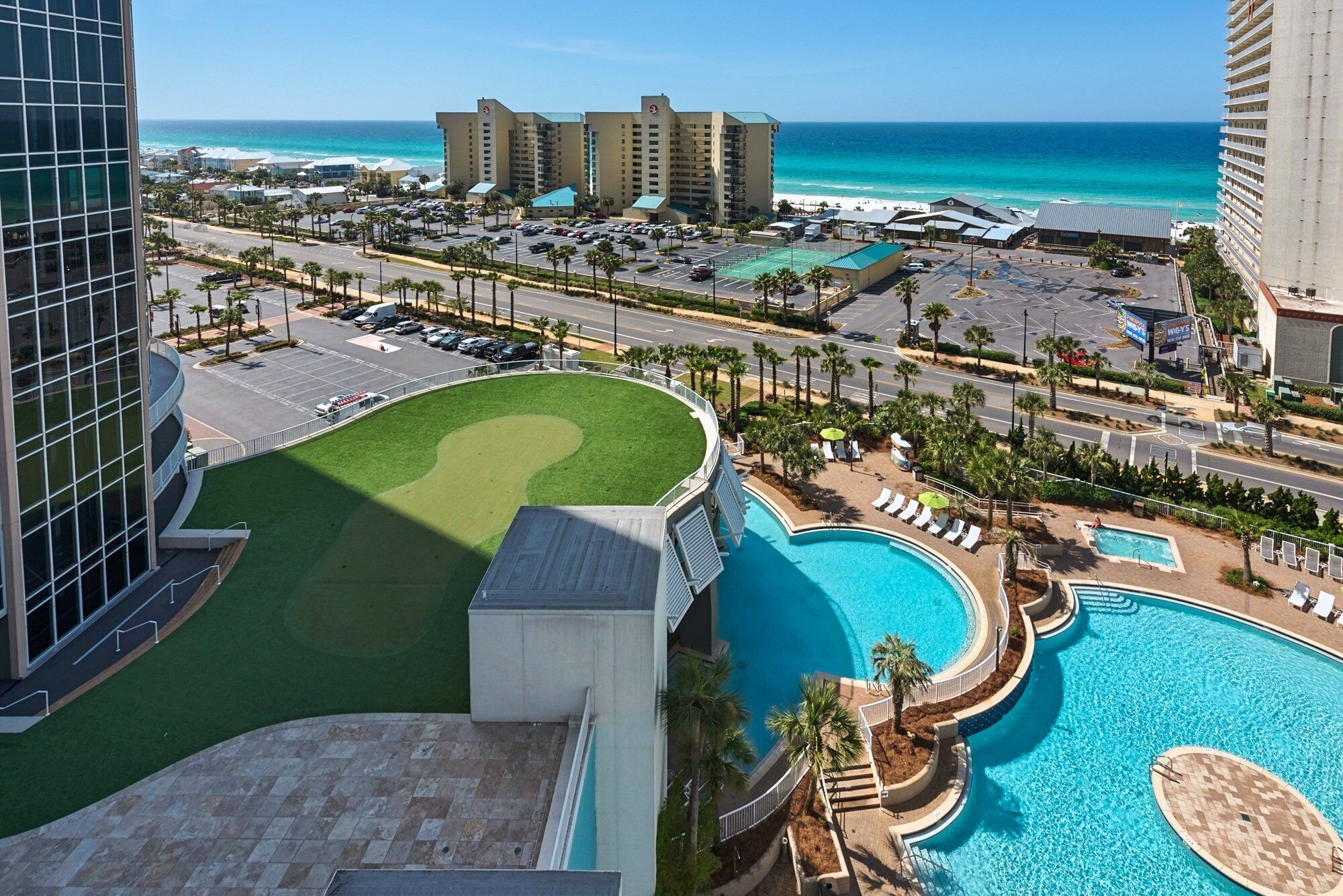 Een resort met een groot zwembad, een golfbaan en uitzicht op de oceaan.