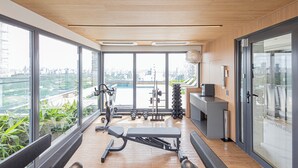 Une salle de sport moderne, équipée de machines de musculation, dotée de grandes fenêtres et offrant une vue sur le paysage urbain.