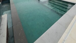 Une piscine sur le toit offrant une vue sur le paysage urbain, entourée d’immeubles modernes.