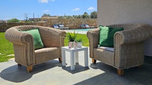 A patio with wicker furniture and a small table, overlooking a pool and greenery. - Cava Del Mar: comfort and relaxation in a vacation home with bedroom, living room and bathroom. (Augusta)