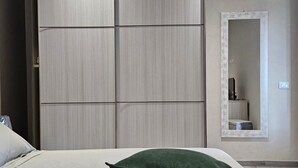 A modern bedroom with a large bed, two green pillows, a wardrobe, and an air conditioning unit. - Cava Del Mar: comfort and relaxation in a vacation home with bedroom, living room and bathroom. (Augusta)