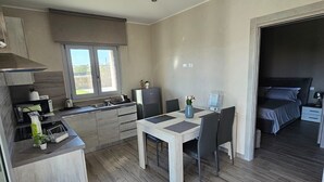 A modern kitchen with a dining area, a small table, and a bed in the adjacent room. - Cava Del Mar: comfort and relaxation in a vacation home with bedroom, living room and bathroom. (Augusta)