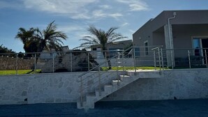 A modern building with a stone staircase leading to a flat roof, surrounded by palm trees and a clear sky. - Cava Del Mar: comfort and relaxation in a vacation home with bedroom, living room and bathroom. (Augusta)