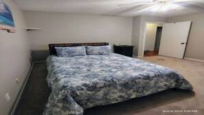 Un dormitorio con cama, ventilador de techo y puerta que da a otra habitación.