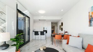 Una sala moderna con un sofá, una mesa de centro y un comedor con sillas y una mesa.