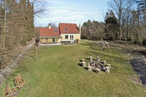 A house with a red roof, a small porch, and a fire pit in the yard.