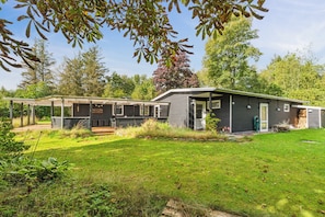 A two-story building with a covered patio area, a small deck, and a well-maintained lawn.