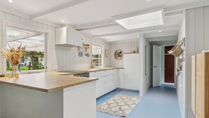 Een moderne keuken met witte kasten, een houten aanrecht en een dakraam.
