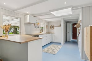 A modern kitchen with white cabinetry, a wooden countertop, and a skylight.