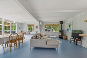 A modern living room with a sofa, dining table, chairs, a fireplace, and a television.