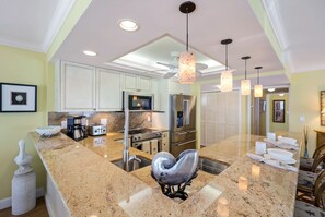 A spacious kitchen with granite countertops, stainless steel appliances, and pendant lighting. - Beachfront Villa! Beachside Pool! Beautiful Sunsets! Nearby Shopping & Dining! (Naples)