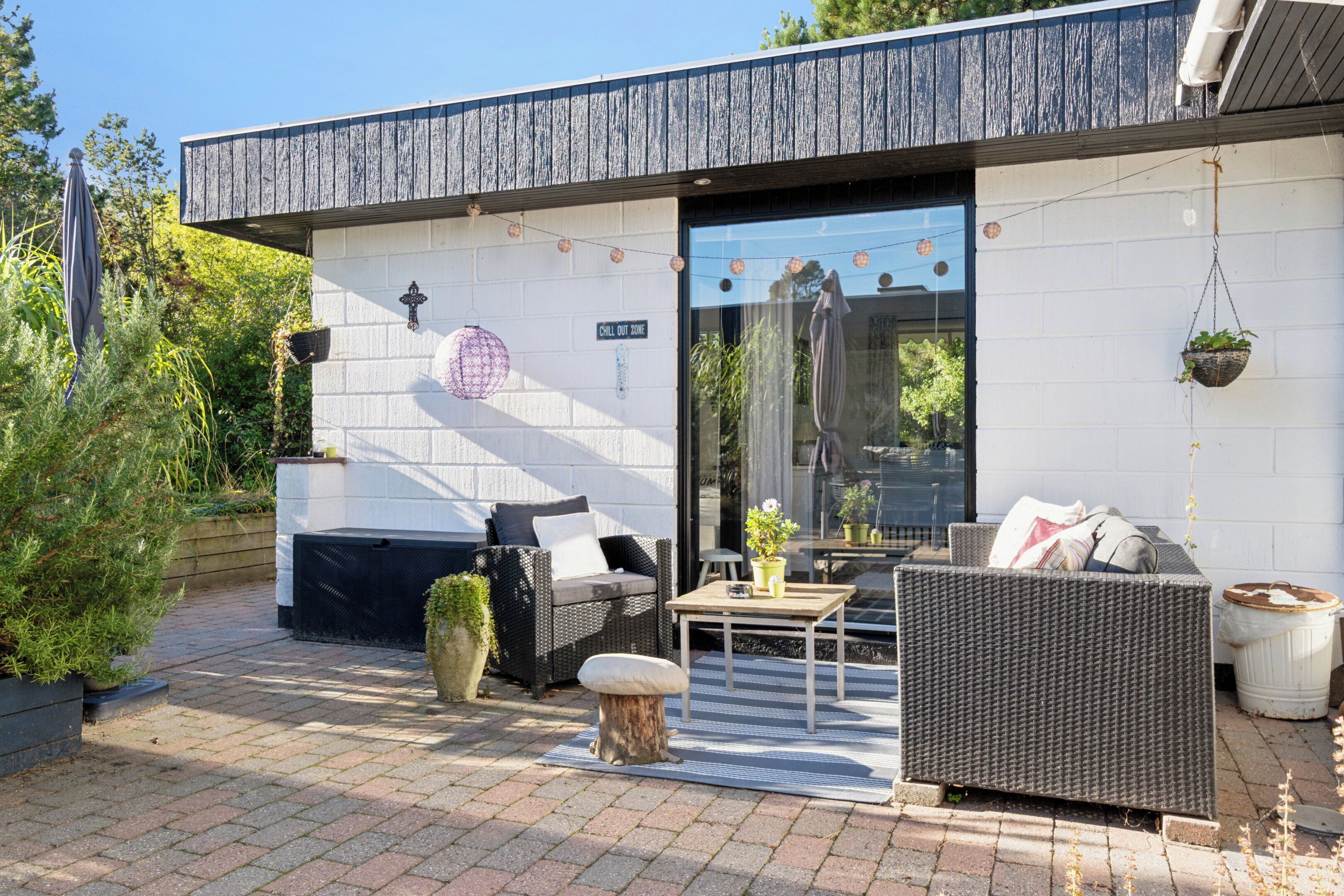 A modern outdoor seating area with wicker furniture, a small table, and a grill.