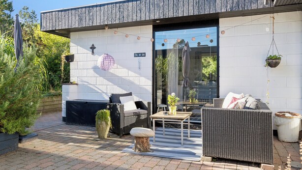 Un espace extérieur aménagé de façon moderne, avec des meubles en osier, une petite table et un barbecue.