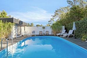 A swimming pool with lounge chairs and a wooden deck. - Holiday home with pool, terraces, near beach (Sjællands Odde)