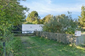 Ein eingezäunter Garten mit Holzfence, einem Briefkasten und einem weißen Gebäude im Hintergrund.