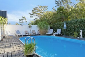 Ein Schwimmbecken mit Liegestühlen und einer Zimmerpflanze.