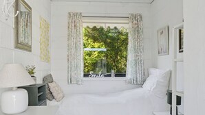 Une chambre à coucher comprenant un lit, une table de chevet, une lampe, une fenêtre avec des rideaux et un miroir fixé au mur.