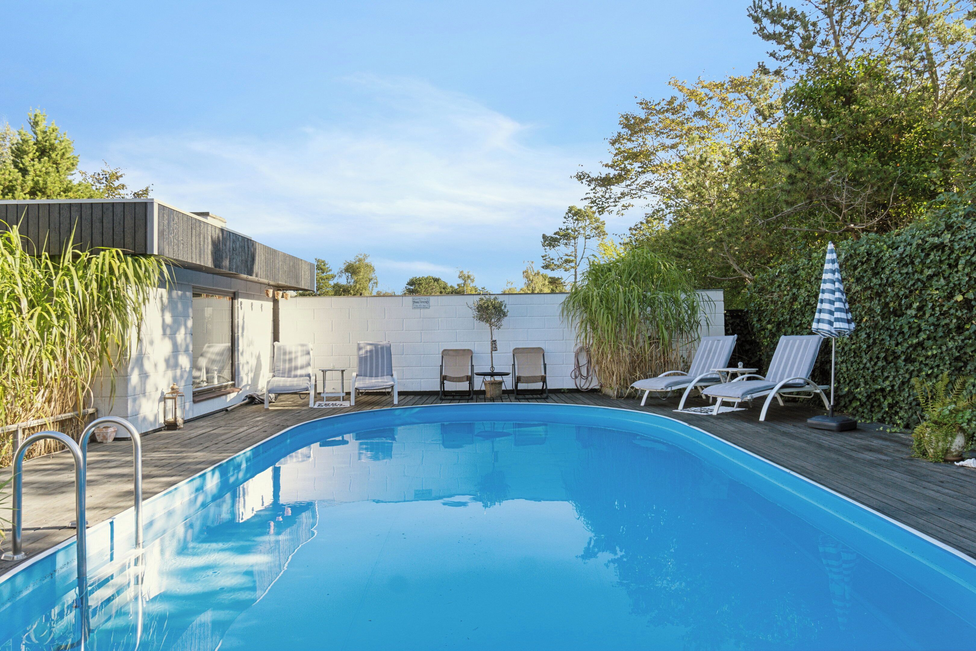 A swimming pool with lounge chairs and a wooden deck.