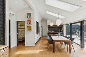 A modern kitchen with a dining area, wooden flooring, and a view through large windows. - Bright holiday home near Ordrup (Fårevejle)