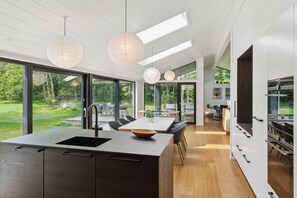 A modern kitchen with a central island, large windows, and a dining area with chairs. - Bright holiday home near Ordrup (Fårevejle)