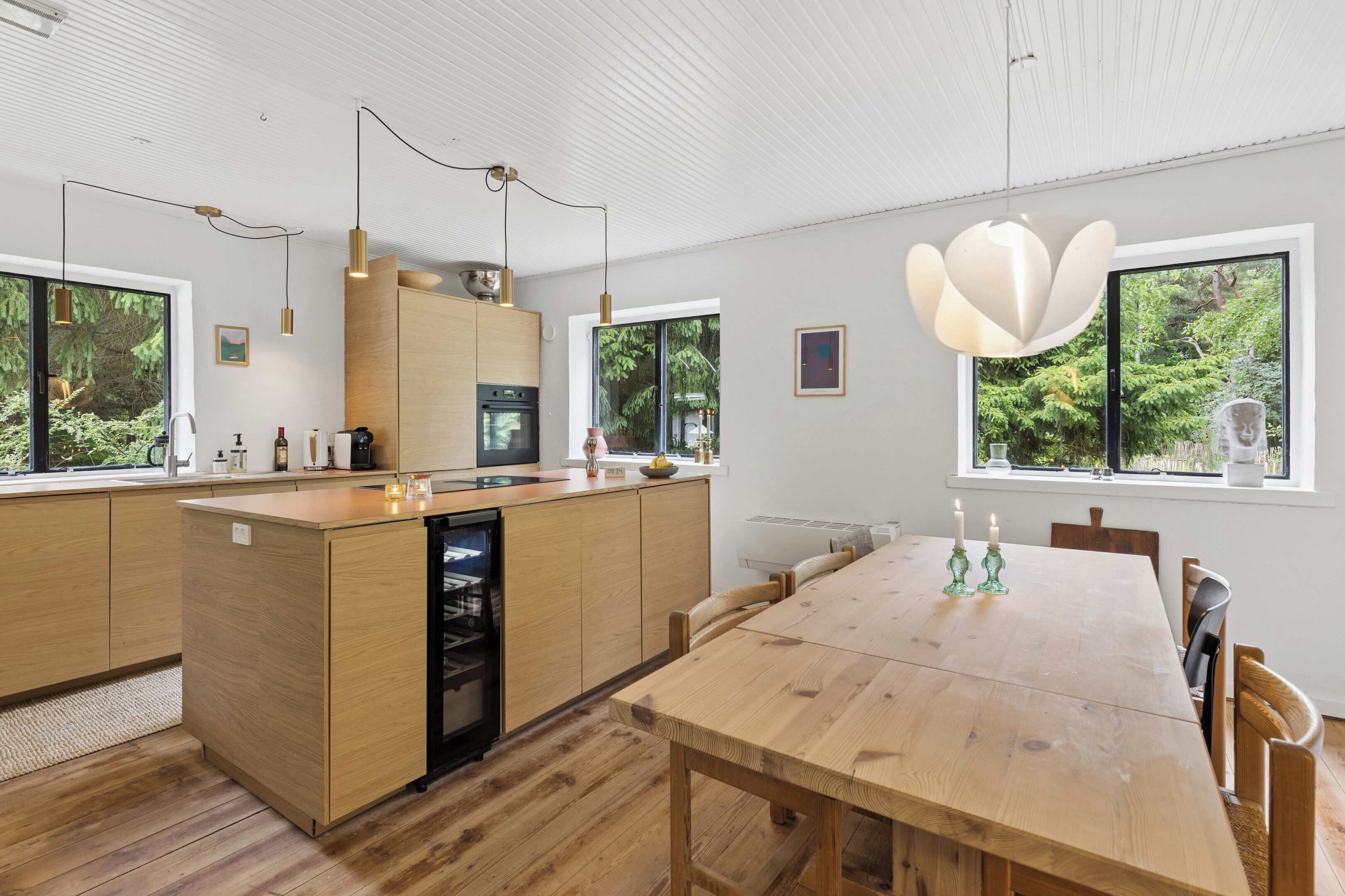Une cuisine moderne avec des meubles en bois, un îlot central et des luminaires suspendus.