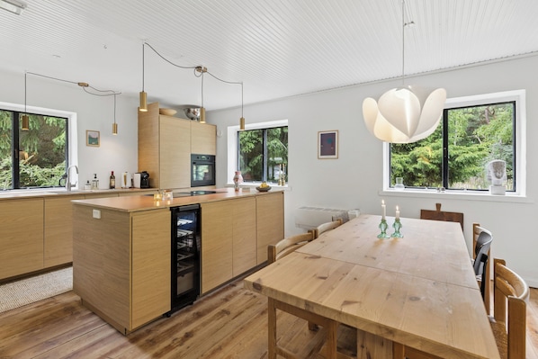 A modern kitchen with wooden cabinets, a central island, and pendant lighting.