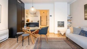 Un espacio habitable compacto con comedor, kitchenette y zona de estar con sofá y una mesa pequeña.