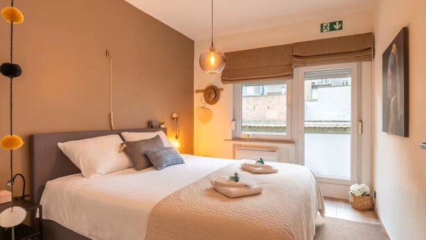 Habitación de hotel con una cama grande, mesitas de noche, una ventana con vistas y una puerta con señal de salida.