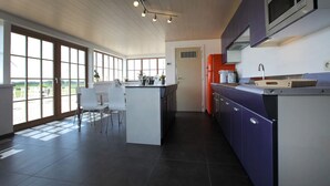 A modern kitchen with a large island, white chairs, and a view through the windows. - Ground floor Standard room - Musterd (Ieper)