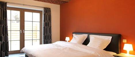 A hotel room with a large bed, a brick ceiling, and a view through a sliding door.
