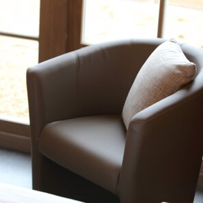 A brown leather armchair with a cushion, positioned near a window with a view of a courtyard. - Ground floor Standard room - Musterd (Ieper)