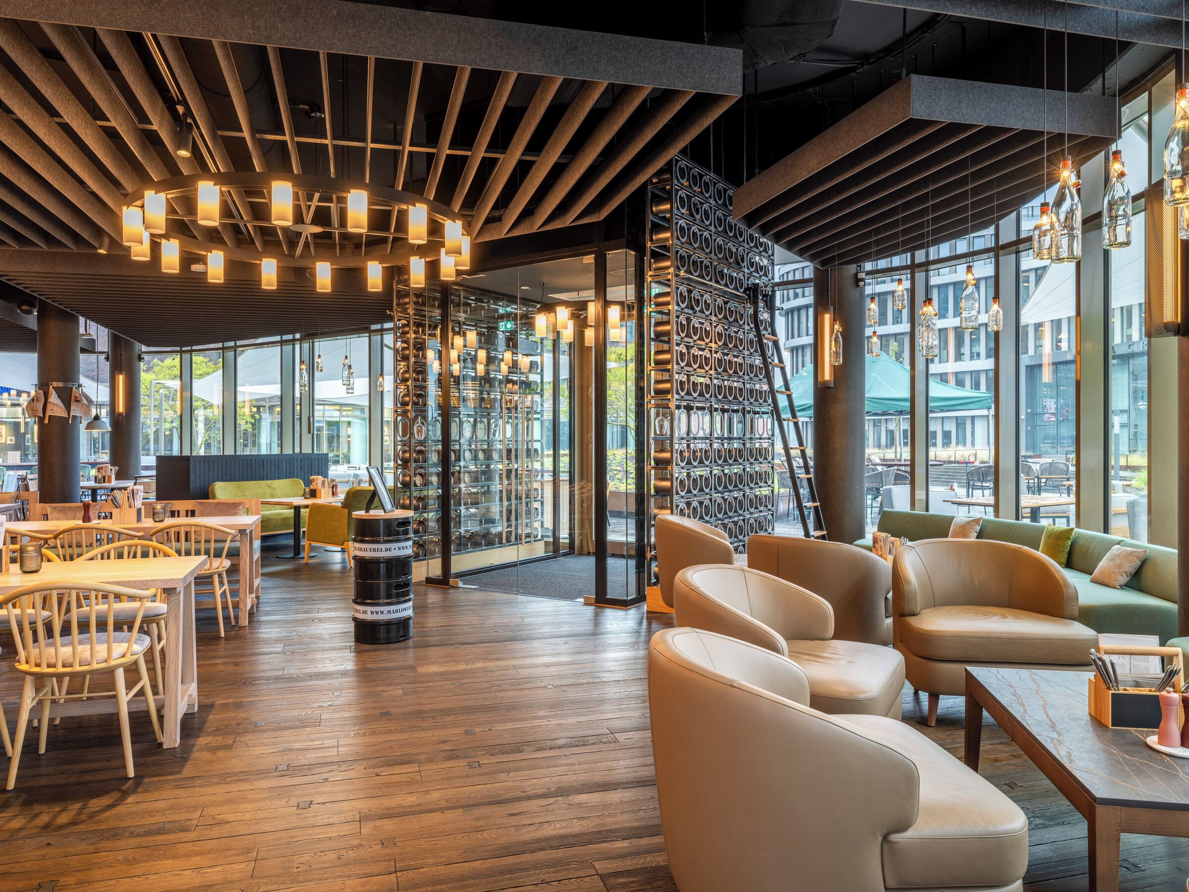 A modern interior with wooden flooring, leather seating, and a wall of hanging bottles.