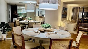 A round dining table with woven chairs, a central plant, and placemats. - Oceanfront Sanctuary with 3 bedrooms (Fort Pierce)