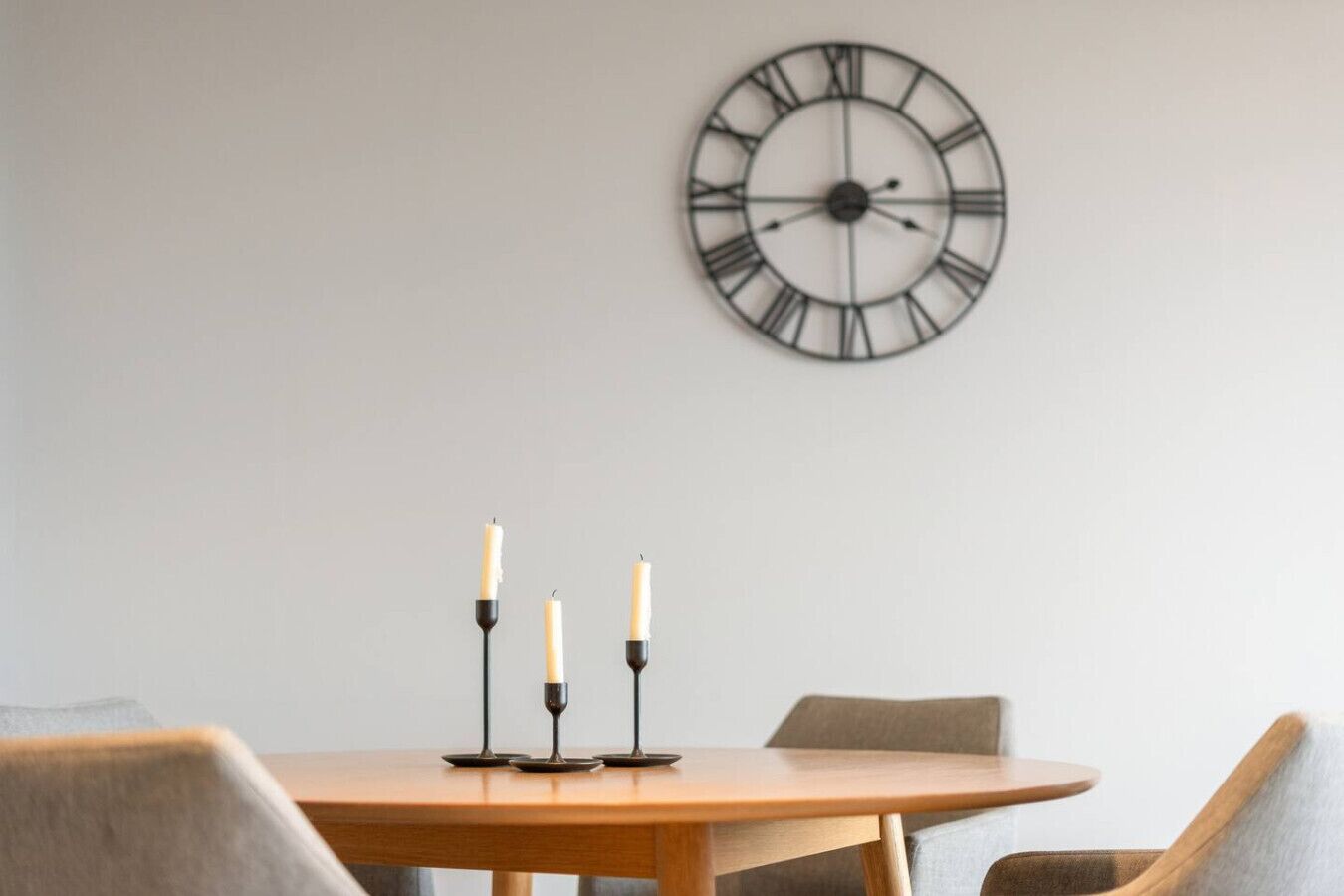 Een eettafel met drie kaarsen en een wandklok.