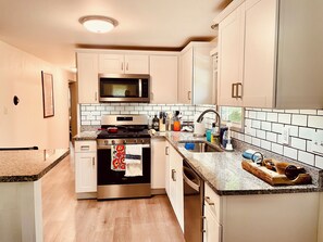 Una cucina moderna con elettrodomestici in acciaio inossidabile, mobili bianchi e piastrelle a parete.