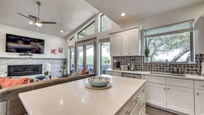 Een moderne keuken met een groot eiland, witte kasten en een ingebouwde oven.