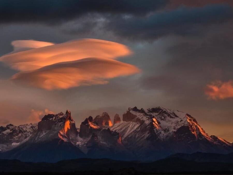 A mountain range with snow-covered peaks and a sunset sky.