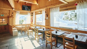 A wooden cabin with a dining area featuring tables and chairs, large windows, and a wooden ceiling. - Chalet Morel 1586 - Hotel & Spa (Limone Piemonte)
