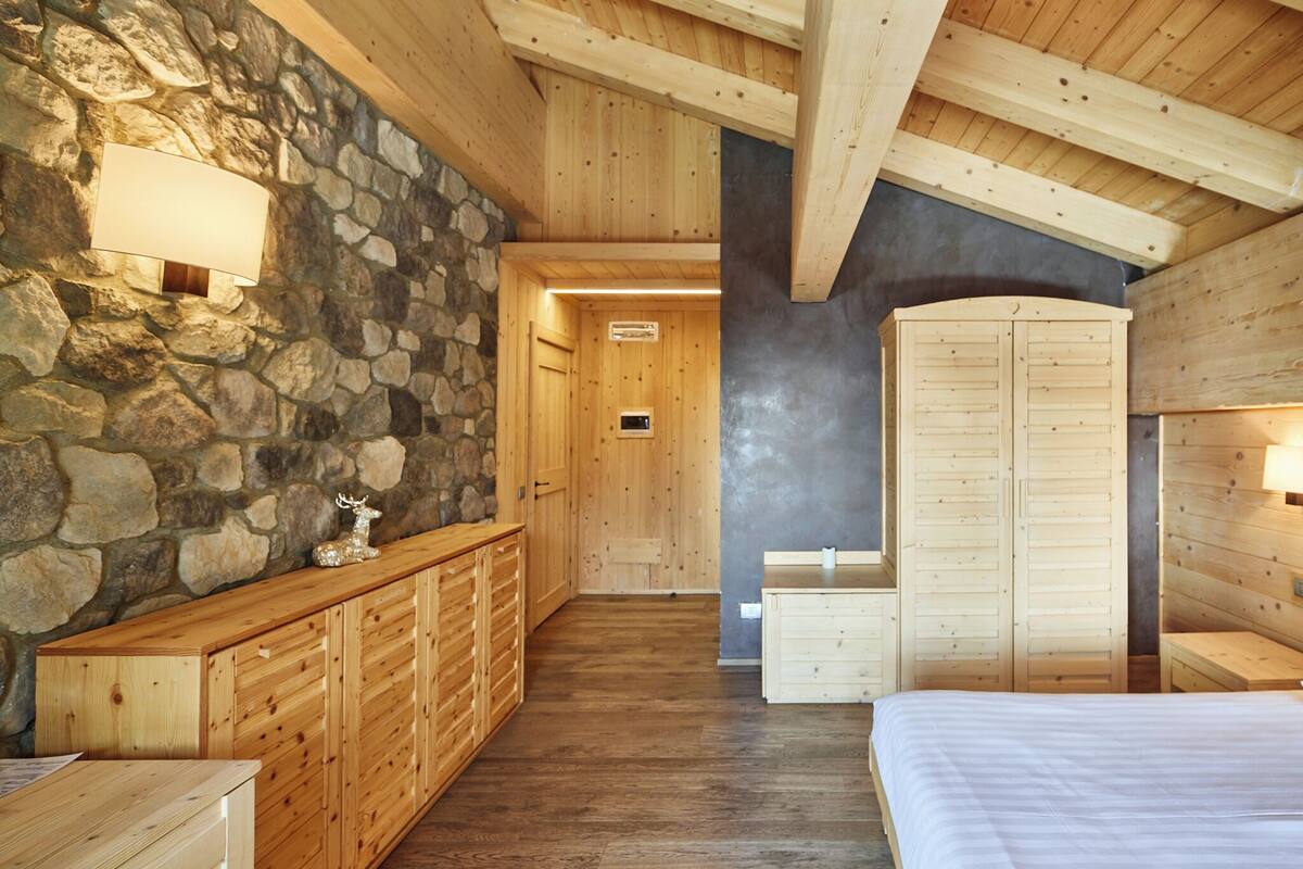 A wooden interior with a stone wall, wooden cabinets, and a bed.