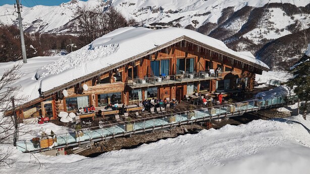 A wooden chalet with a glass bridge leading to a dining area, surrounded by snow-covered mountains. - Chalet Morel 1586 - Hotel & Spa (Limone Piemonte)