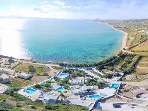 Luchtbeeld van een kustgebied met woonhuizen, een strand en een heldere blauwe zee.