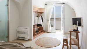 Een slaapkamer met een bed, nachtkastje, televisie, verwarming, garderobe en een balkon met uitzicht.