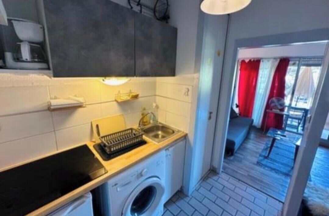 Una cocina compacta con lavadora, pileta y una pequeña mesada.