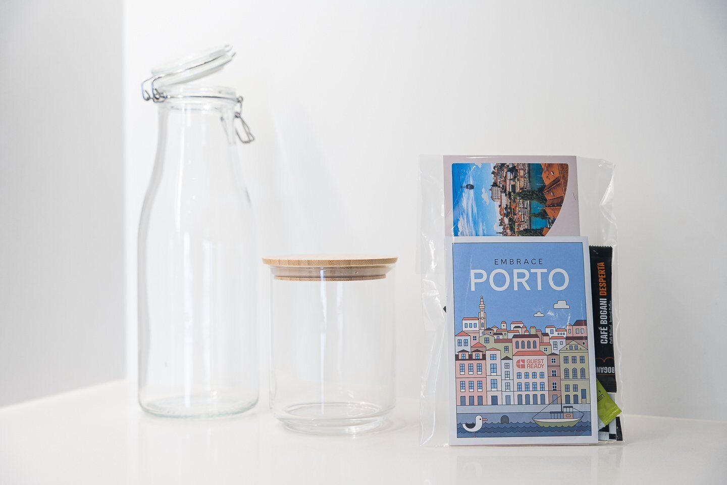 A clear glass pitcher, a small glass jar, and a travel guidebook titled 'Embrace Porto'.